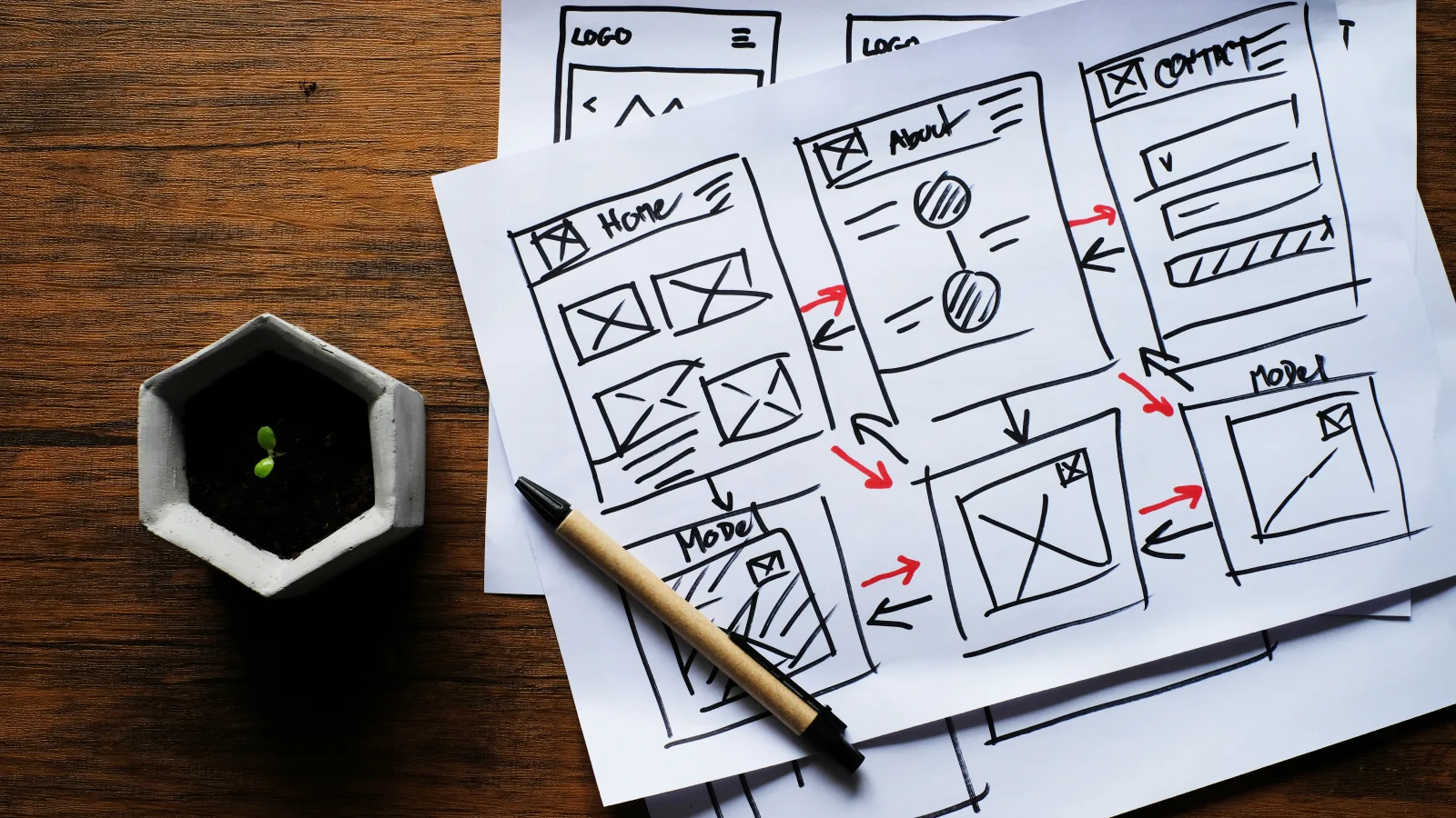Handgezeichnete Website-Wireframes auf Papier auf einem dunklen Holztisch