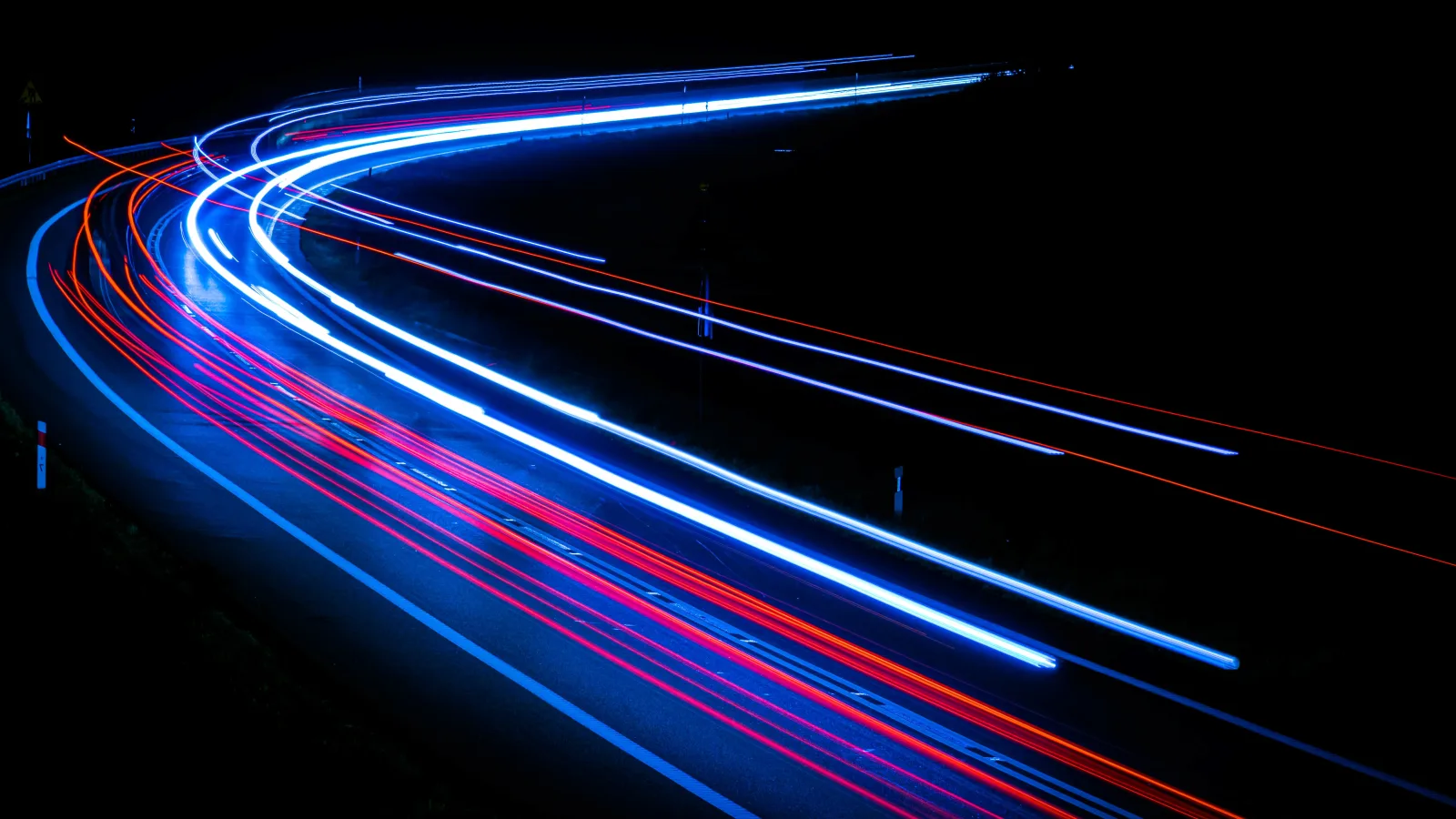 Lichtspuren fahrender Autos bei Nacht als Sinnbild für Geschwindigkeit